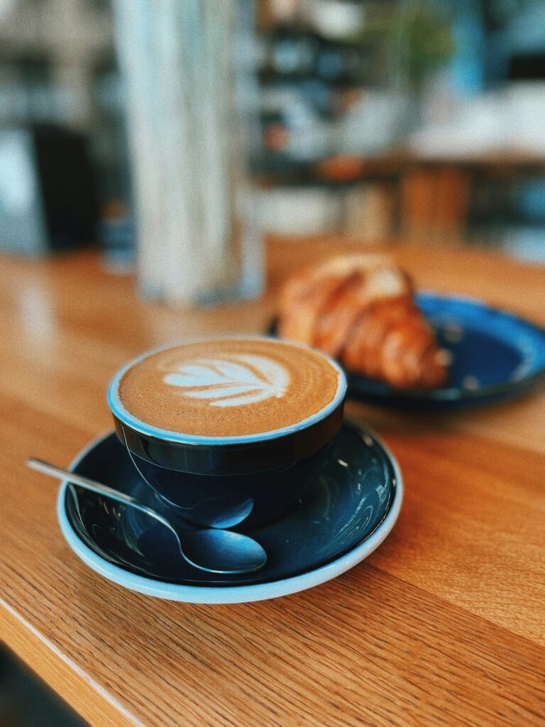 A cappuccino and a croissant on a wooden table