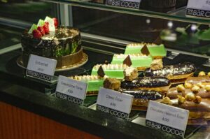 A display case filled with cakes, pastries and eclairs